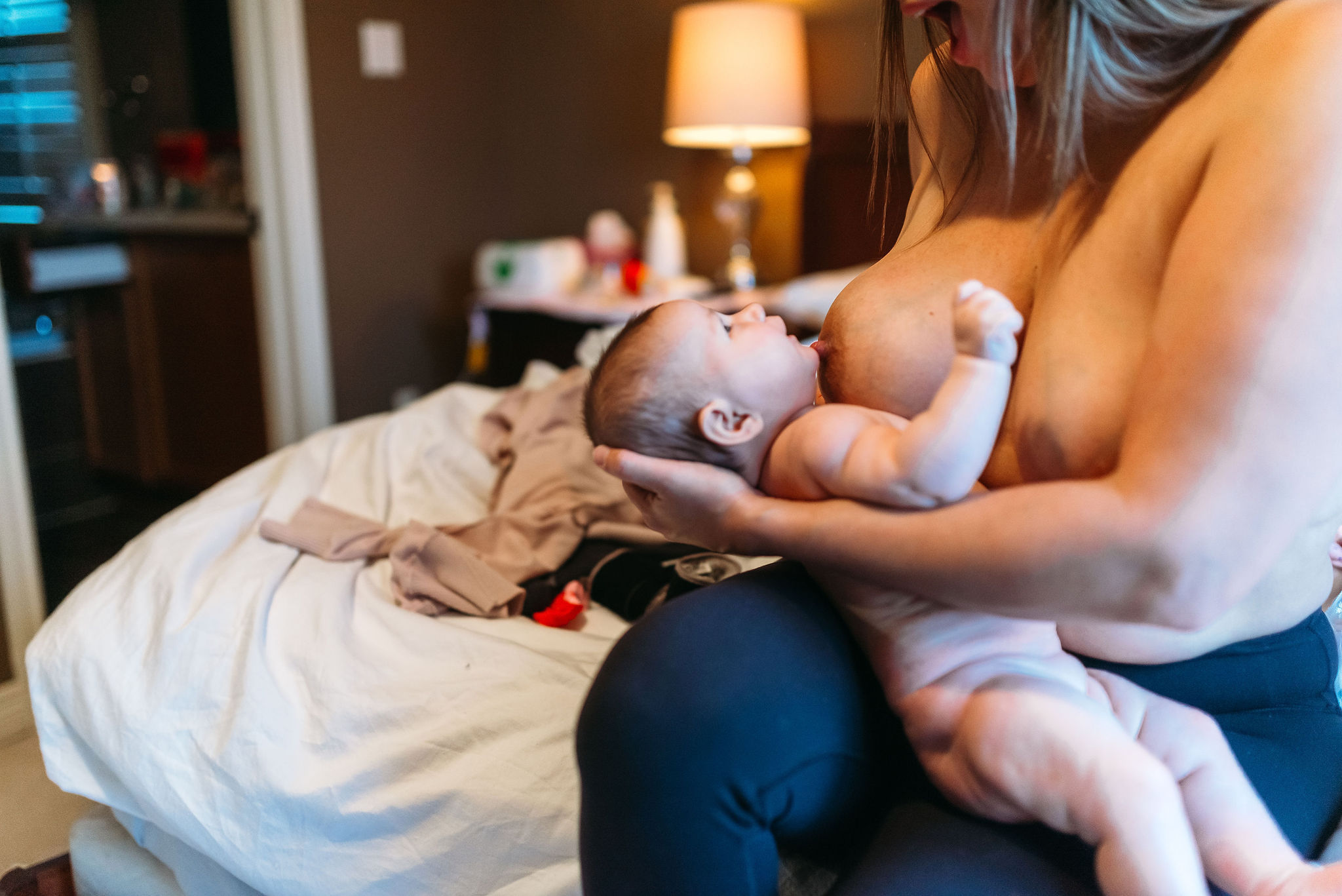 Mother breastfeeding her newborn while seated at home